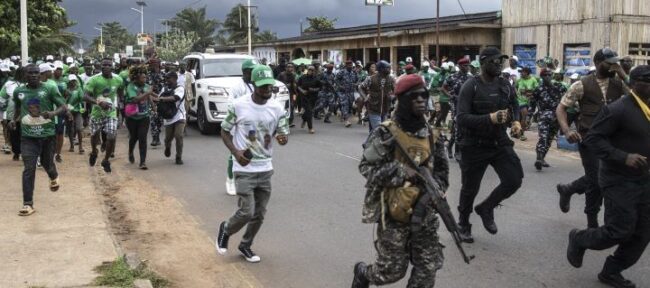 Les partisans et les membres de la sécurité du président de la Sierra Leone, Julius Maada Bio, courent à côté de sa voiture lors de leur dernier rassemblement de campagne à Freetown, le 20 juin 2023 1